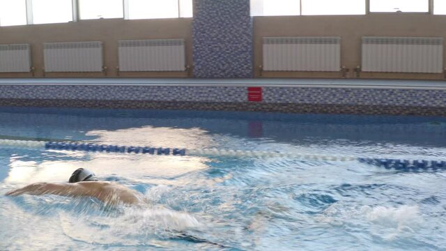 A professional sportsman is swimming in the swimming pool