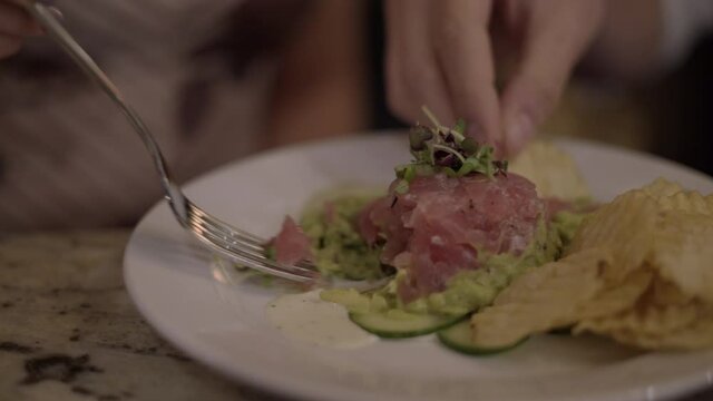 Close Up of Man and Woman Hands Eating Chips and Tuna Avocado Poke Tower