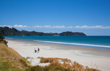 Tourists walking down Onetangi Beach at Waiheke Island off Auckland, New Zealand.
