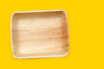 Betel palm leaf plates on yellow background.