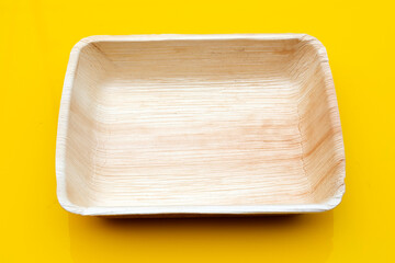 Betel palm leaf plate on yellow background.