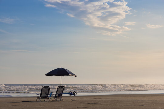 Cadeiras, guarda-sol e carrinho ho isolados em praia ensolarada. Litoral Norte de S&atilde;o Paulo, Guaratuba, Bertioga. 