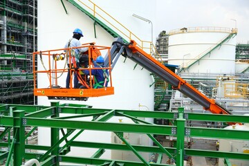 Worker are driving the Orange articulate boom lift or telescopic boom lifts and bucket crane mounted on truck to safety for working at heights and articulating boom lift reaching high up.