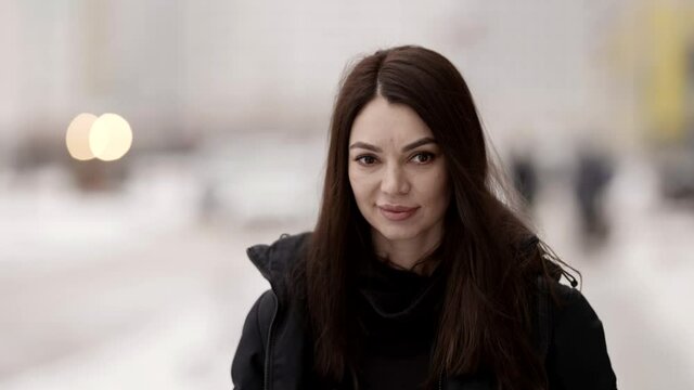 winter walk in city, portrait of smiling woman outdoors on snowy street in megapolis, charming face