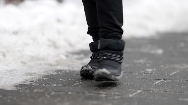 passerby is walking on street at winter day, closeup of feet shod warm shoes outdoor