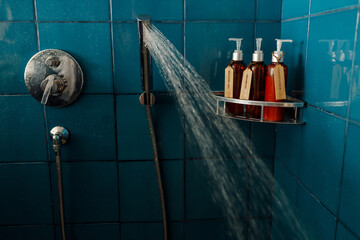 Shampoo, conditiones and shower gel dispensers in brown bottles on te shelf in blue bathroom shower