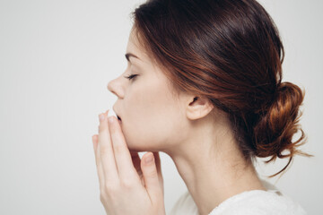 Fototapeta premium brunette woman wipes her face with a white sponge on a light background