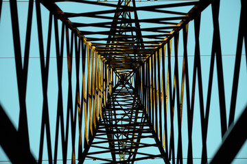 Bottom view: power line against the blue sky in the winter forest, silhouette. Hi-voltage electrical pylons