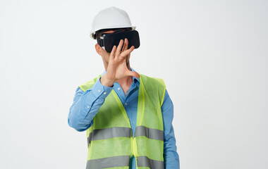 A man builder in a yellow vest and a white helmet with a roll of paper in his hand repairing work