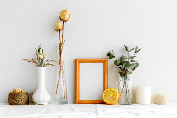Wooden photo frame and dried plants in vases on a white background. Minimalistic, gentle summer layout. Blank for a postcard. Interior for design.