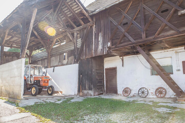 Fototapeta na wymiar Old barn with a tractor in an Alpine village in Slovenia