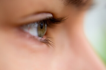 Profile view of green eye looking straight forward with no makeup natural look with light shining...