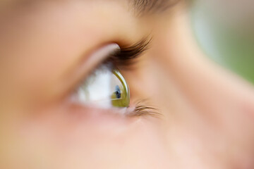 Profile view of green eye looking straight forward with no makeup natural look with light shining...