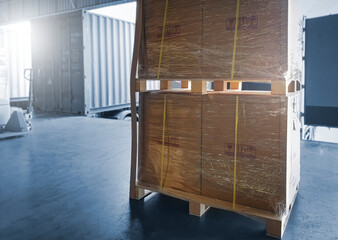 Stacked large boxes wrapped plastic on pallet rack. Trailer parked at loading dock warehouse. Cargo shipment load for truck. Industry freight truck transportation.