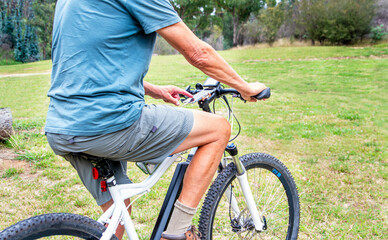 Naklejka premium adult male on electric bike operating mobile phone for navigation being charged from the bike battery