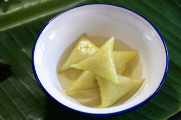 Dessert made with glutinous rice wrapped in banana leaves, triangle shape, boiled, eaten with syrup and ice. Thai Dessert; called Kao Tom Nam Woon. 