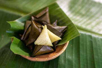 Dessert made with glutinous rice wrapped in banana leaves, triangle shape, boiled, eaten with syrup and ice. Thai Dessert; called Kao Tom Nam Woon. 