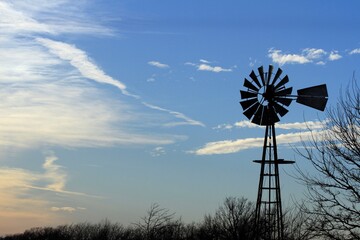 Kansas Windmill at Sunset with blue sky and white clouds north of Hutchinson Kansas USA out in the country.