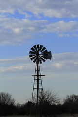 Kansas Windmill at Sunset with blue sky and white clouds north of Hutchinson Kansas USA out in the country.