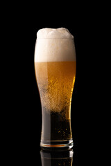 glass of beer with bubbles and thick white foam, isolated on black background