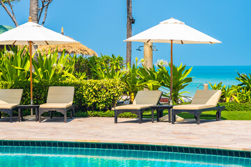 Outdoor swimming pool with sea ocean beach around umbrella and chair