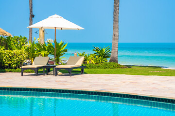 Outdoor swimming pool with sea ocean beach around umbrella and chair - 413437673