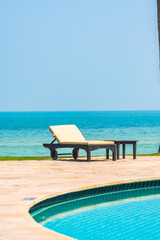 Outdoor swimming pool with sea ocean beach around umbrella and chair
