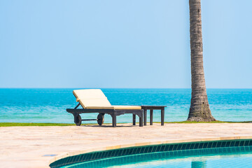 Outdoor swimming pool with sea ocean beach around umbrella and chair