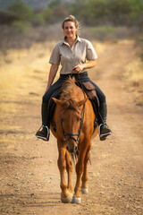 Smiling blonde rides horse on dirt track