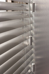 Aluminum blinds on the office windows. Made from metal. Venetian blinds closeup on the window. Silver color. Closed horizontal blinds in sunny day. Modern sun protection and window decoration