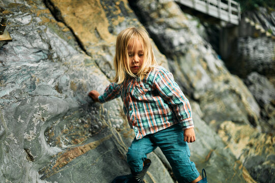 Preschooler climbing on rocks in the autumn