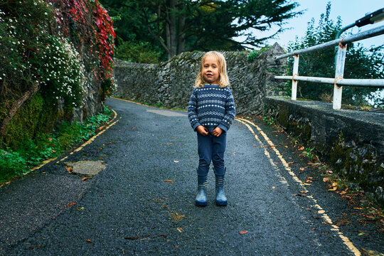 Preschooler standing outdoors in the road on autumn day