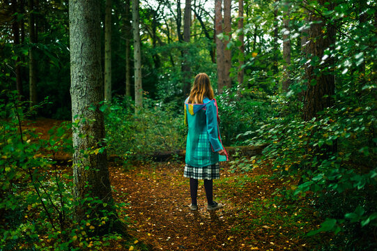 Young woman wearing raincoat walking in the forest on an autumn day