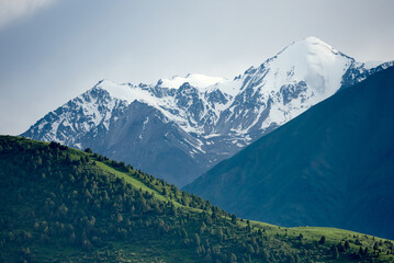 Fototapeta premium Summer mountain landscape of Kyrgyzstan. Among green valleys, mountains are visible at middle of the day. Tien Shan Mountains, Kyrgyzstan.
