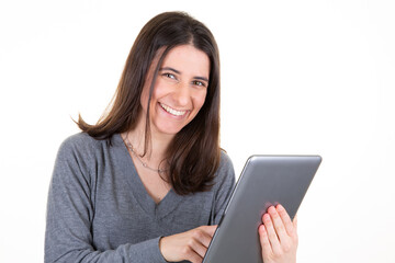 Portrait of smiling woman with long brown hair holding and looking at tablet computer isolated over white background in studio