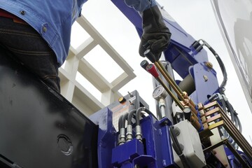 Workers are controlling boom truck or truck loader to upload equipment and machinery into the...