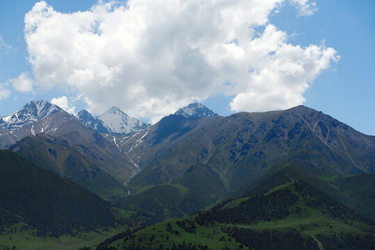 The nature of Kyrgyzstan. Mountain landscape. Among green valleys, mountains are visible at middle of the day. Tien Shan Mountains, Kyrgyzstan.