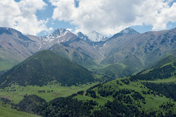 The nature of Kyrgyzstan. Mountain landscape. Among green valleys, mountains are visible at middle of the day. Tien Shan Mountains, Kyrgyzstan.