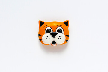Cute orange tiger head toy on a white background isolated. Bright figurine, template for collage flat lay. Funny kids board colored toy. Child's game little stiped single figurine with copyspace.