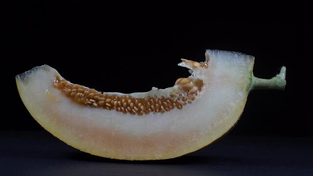 Yellow melon on a black background, close up. Rotates slice yellow melon, macro
