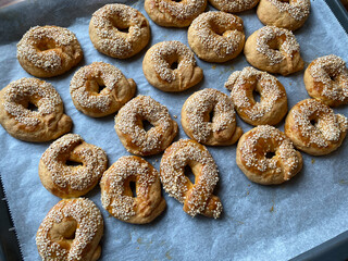 Freshly Baked Turkish Cookies Traditional Simit Bagel Kandil Simidi with Sesame Seeds and Mahaleb on Baking Tray with Paper Sheet.