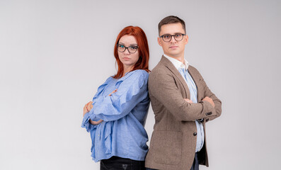 A man and woman businesspeople standing back to back looking at the camera. Boy and girl in glasses. Light gray background behind.