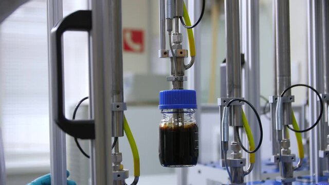 Woman controls putting bottle of oil into testing equipment