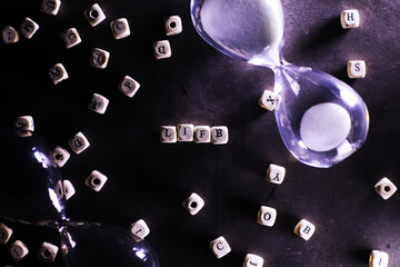 Sand running through the bulbs of an hourglass measuring the passing time in a countdown to a...