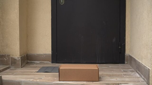 Contactless Doorstep Delivery Service. Courier in protective mask and gloves no contact delivers the parcel box to the home of a woman with a child. Online ordering buying shopping