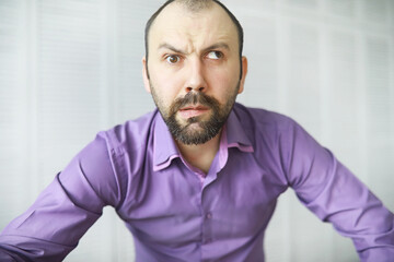 Fototapeta premium A cross-eyed bearded man is looking into the frame. Eye disease. The concept of an inexperienced specialist. Spy neighbor.