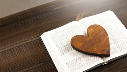Open Bible book on the table. Wooden heart. Book love concept