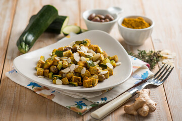 Tofu with zucchini sliced almonds olives turmeric spice and fresh ginger