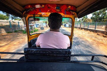 Hampi. India. Cab driver is driving a rickshaw taxi with passengers through the Indian village
