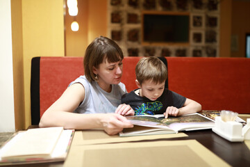 Fototapeta na wymiar Mother with son examines magazine in cafe